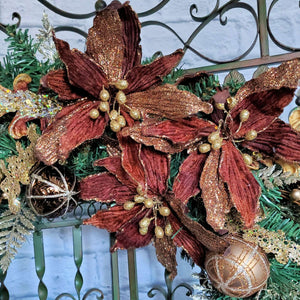 Large velvety brown poinsettia flowers, dusted in gold highlight the wreath. 
