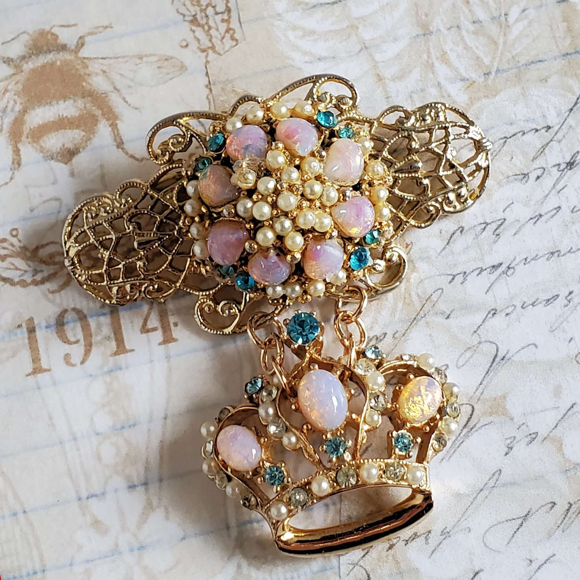 Two tier Brooch with a gold tone filigree setting with an imitation opal, pearl and rhinestone centerpiece. A matching is attached below the upper pin portion.