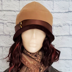 1920s Cloche Hat in a Tan Felt with a Brown Satin Ribbon Band accented with vintage buttons. Hat is finished with a dark brown velvet brim. 
