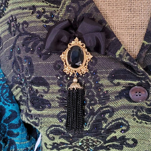 Black and gold brooch pin, pinned on a beaded jacket