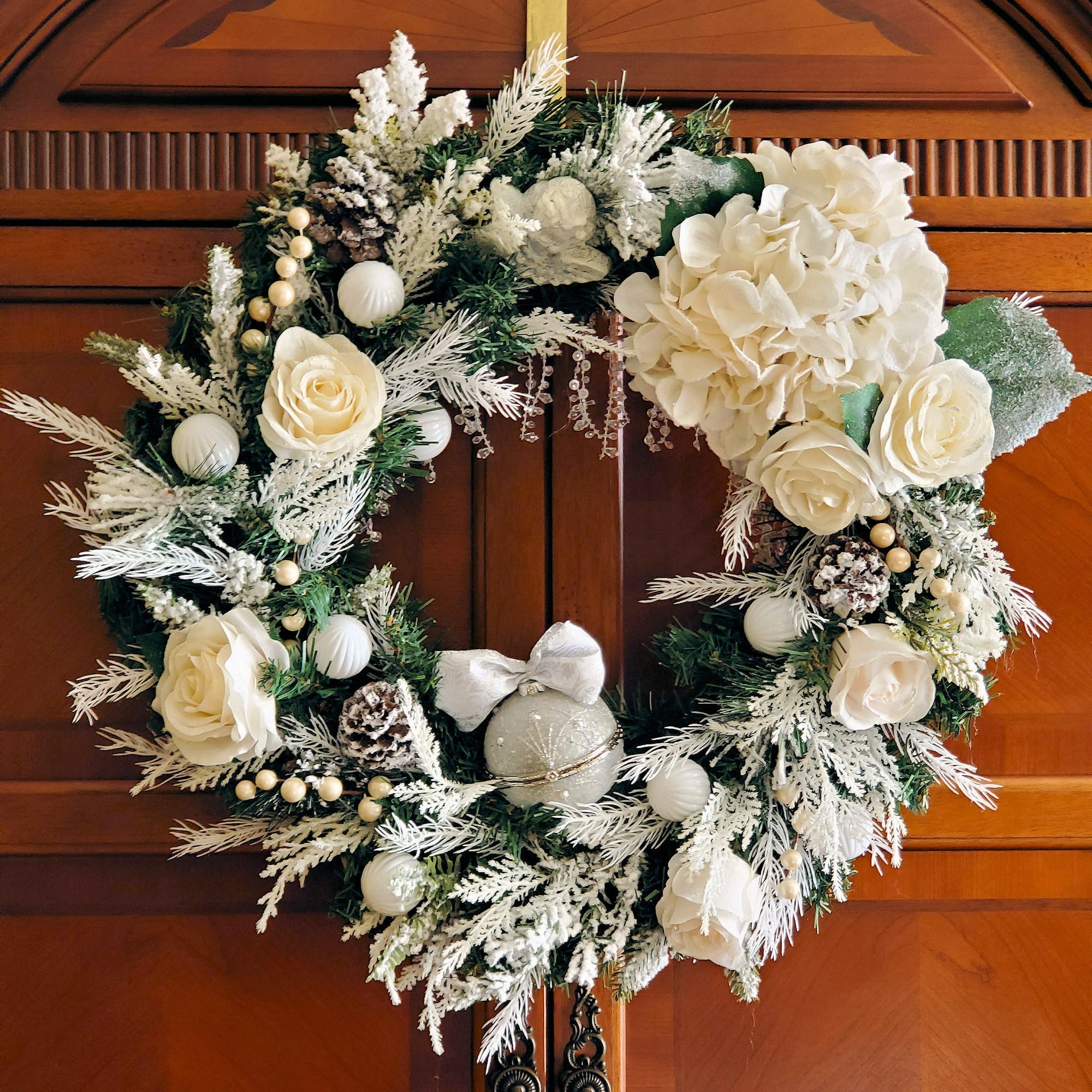 White Pine Branches, White Pearl Berries and Snow  Dusted Pinecones decorate the wreath.