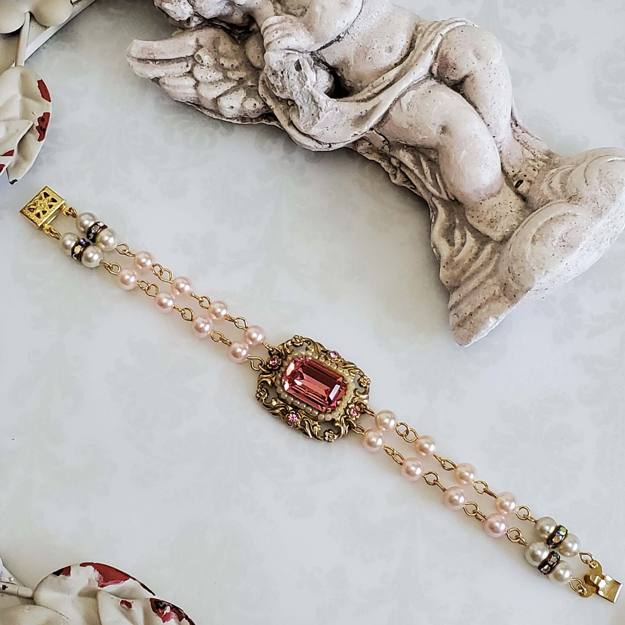 Two Strand Vintage Pearl Bracelet with a Vintage Pink Gemstone  set in a gold tone framed setting.